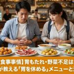 スペインのレストランで油っこい料理を前に胃もたれし、お腹を押さえて困った顔をする日本人観光客